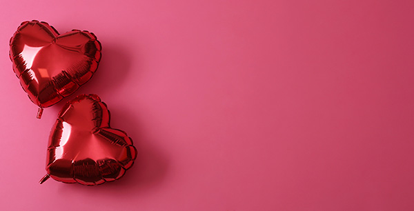 two heart balloons on pink background